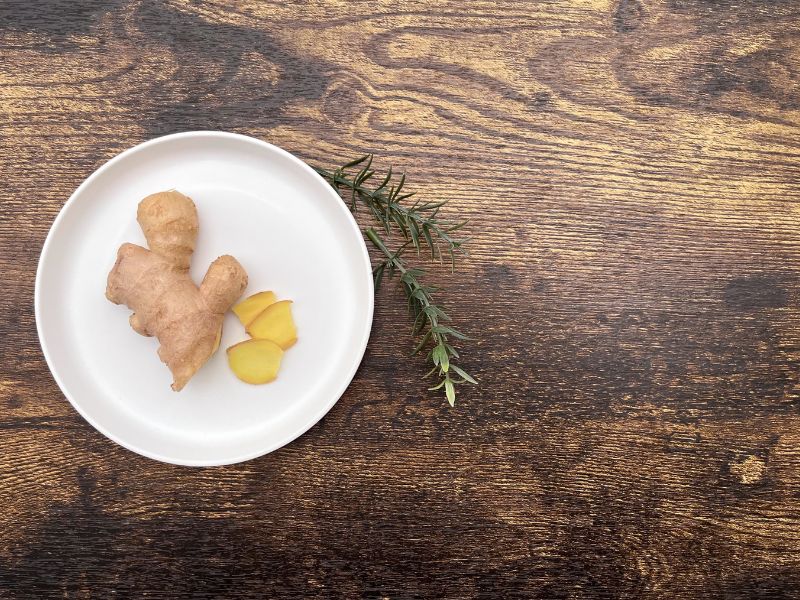 sliced and whole ginger in a bowl with greenery