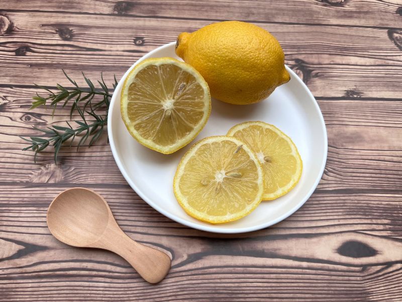bowl of lemons with greenery and a wooden spoon 