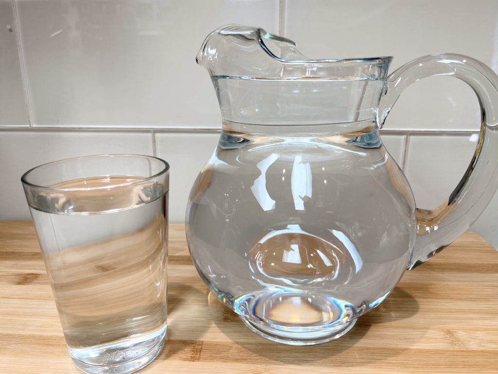 water in a pitcher and in a glass designed for pregnancy hydration blogpost